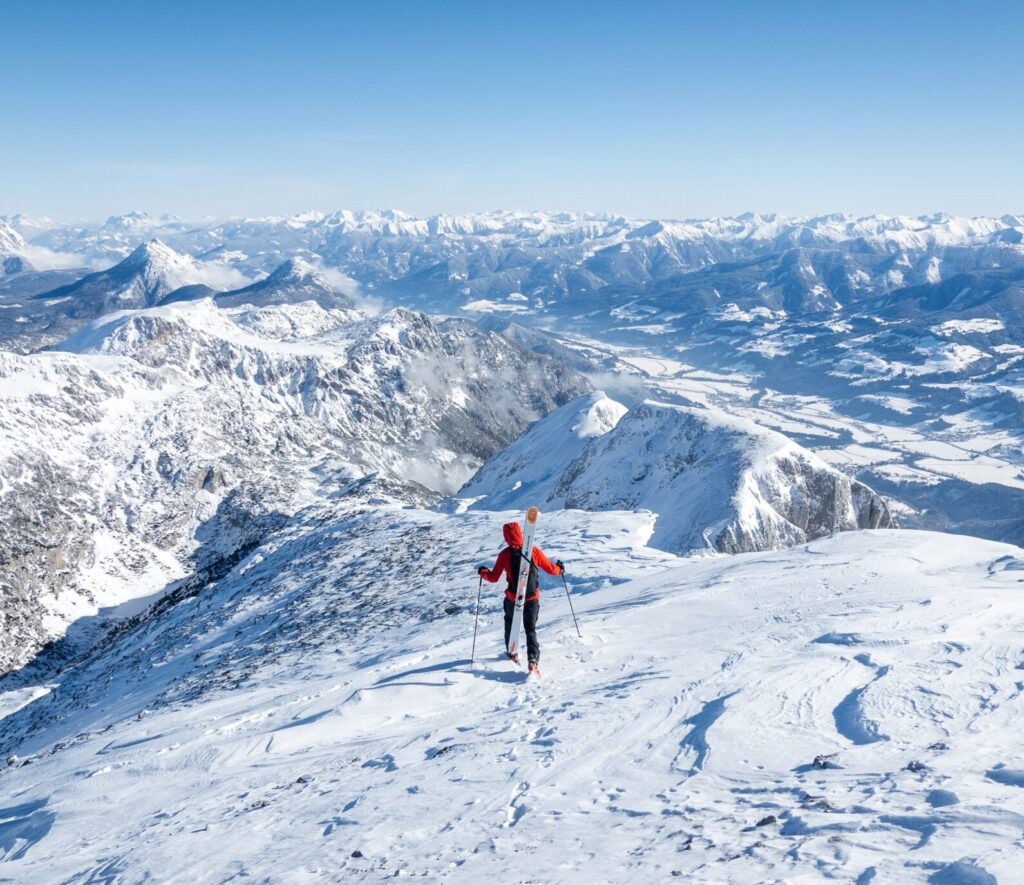 Bjerg miljø med enlig ski løber der står med ski på nakken og kigger ud over sneklædte bjergsider.